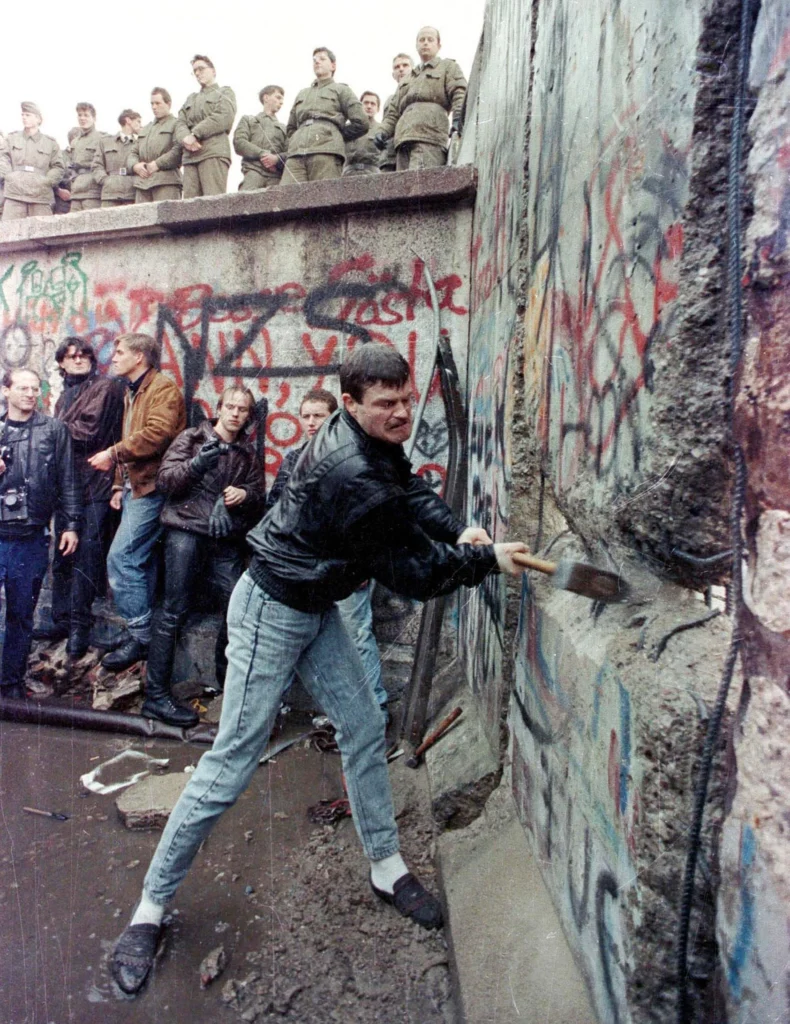 Ein Demonstrant hämmert auf die Berliner Mauer ein, während Grenzsoldaten der DDR vom Brandenburger Tor aus zusehen, 11. November 1989.
Foto: Stringer/Reuters